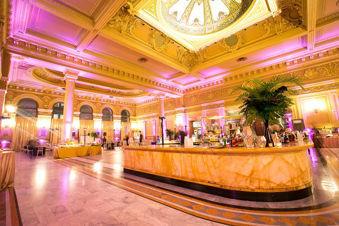 The Hibernia. Elegant historic ballroom venue with grand gold detailing, high ceilings, and a central marble bar set for a formal catered event.